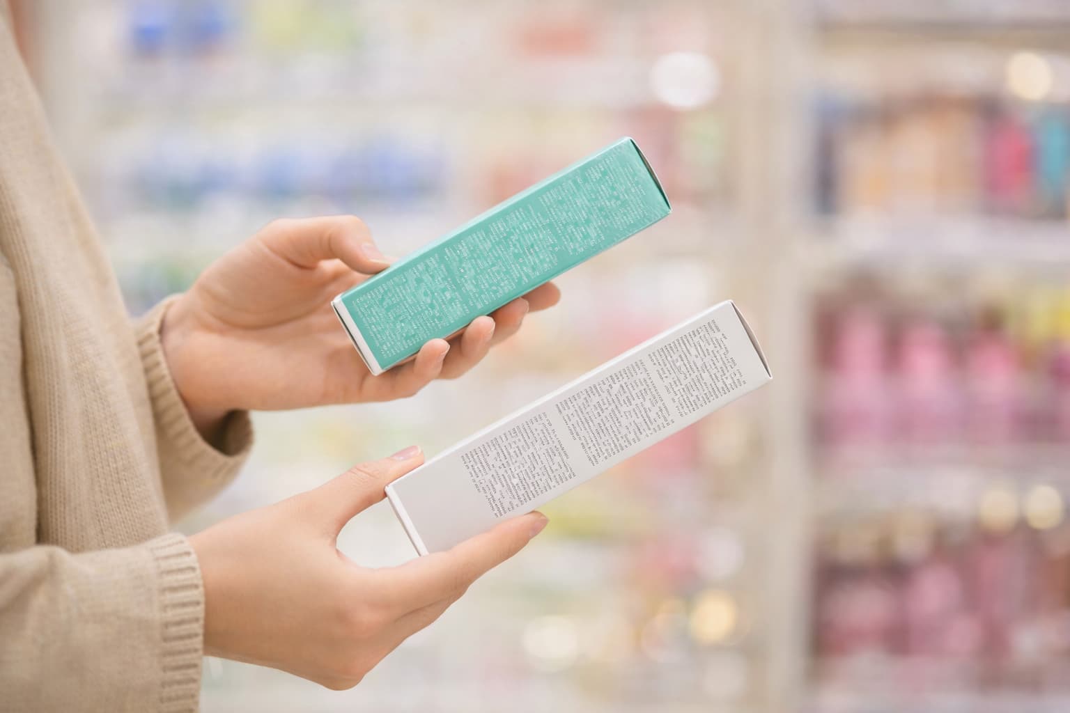 Hände vergleichen zwei Kosmetikverpackungen mit Pflichtangaben – Kosmetik Etiketten selbst gestalten